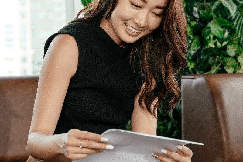 Smiling Asian woman looking at her insurance plans from HL Assurance