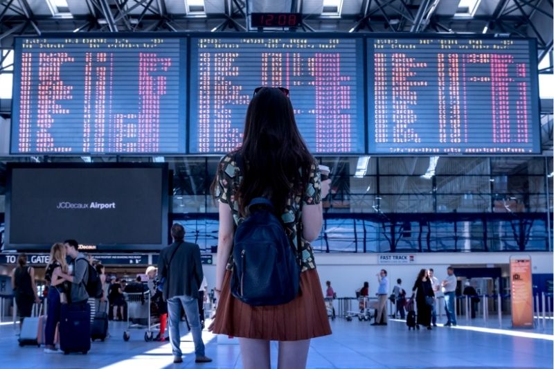 Asian woman at flight schedule in foreign airport